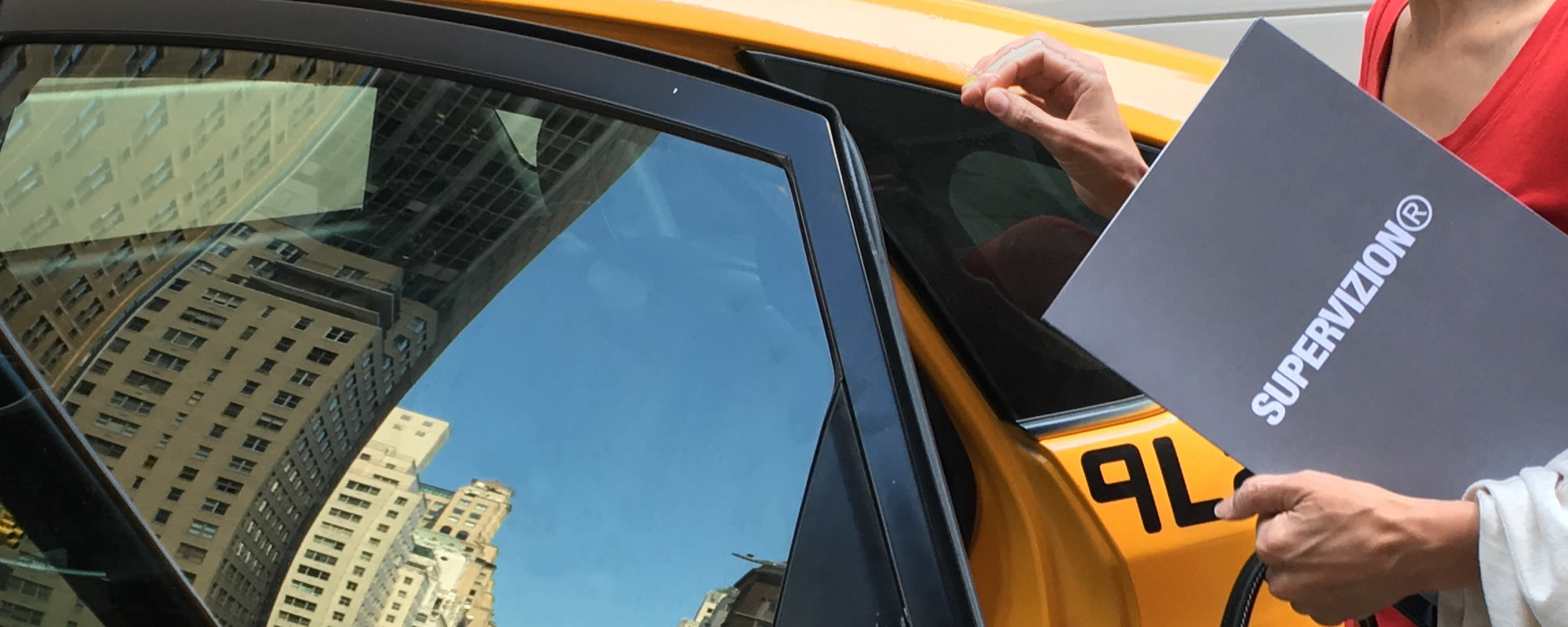Supervizion in New York City, model holding a folder with Supervizion logotype when opening cab door